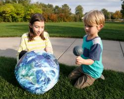 Two children look at an inflatable Earth globe.