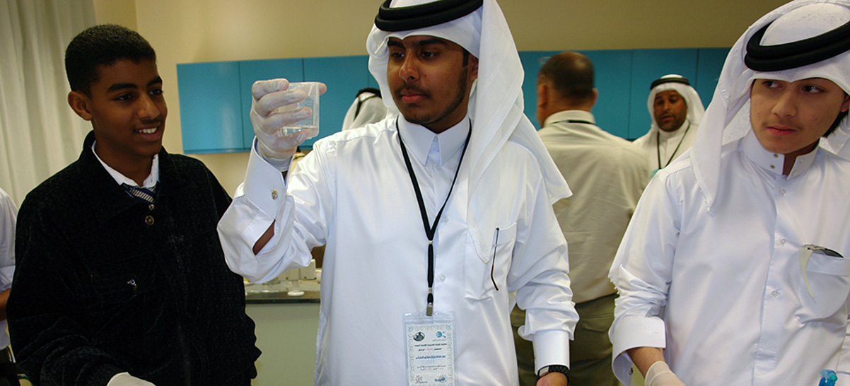 Three students looking at a beaker in a lab.